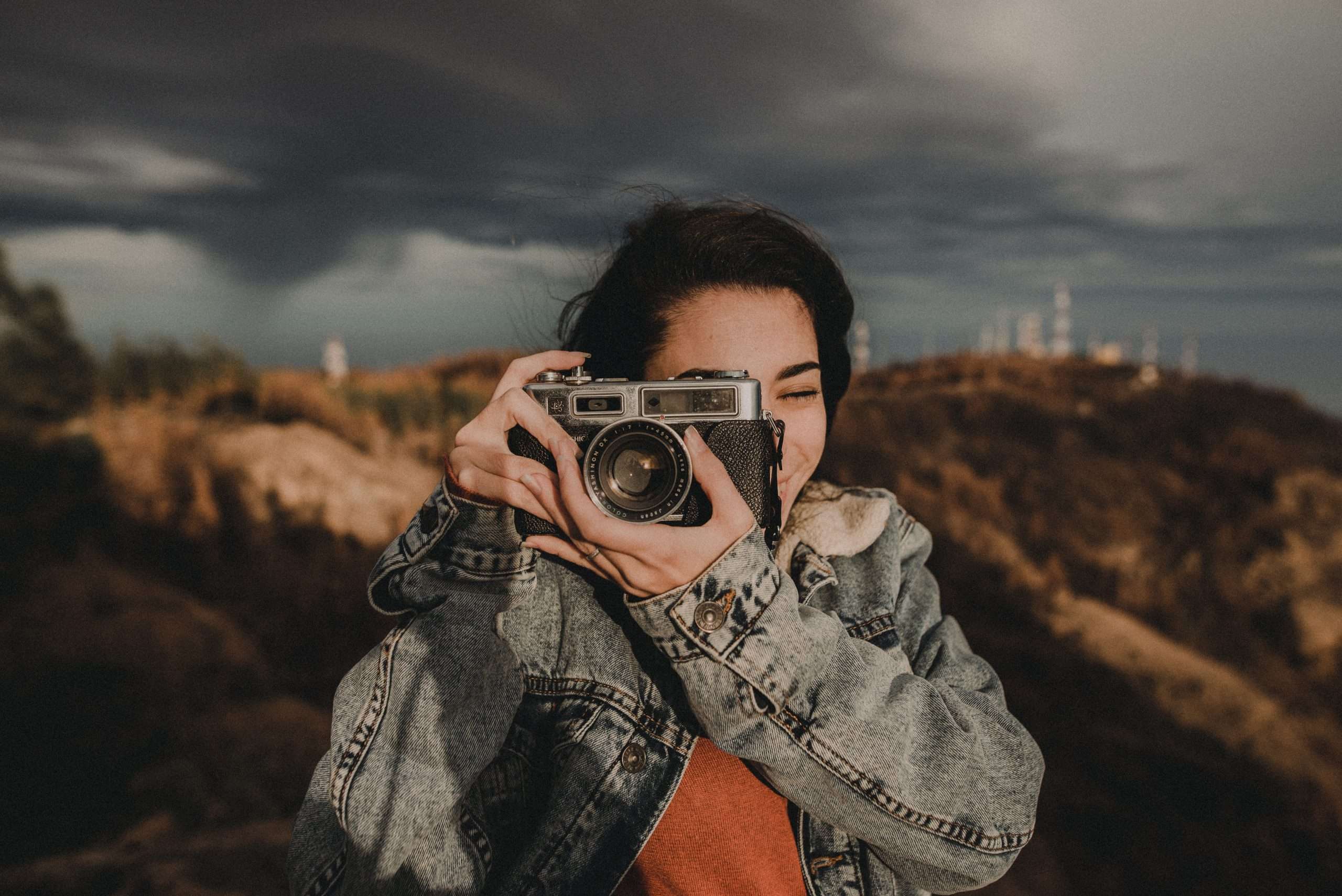 A woman capturing an image with an old camera, demonstrating the basics of photography.