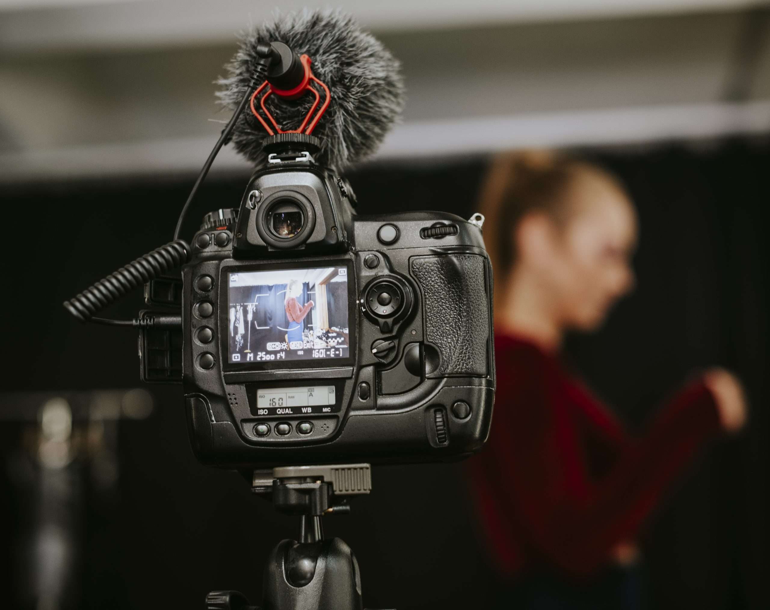 A woman is filming a video with a dslr camera.
