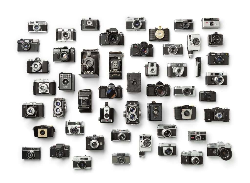 A group of vintage cameras arranged on a white background.