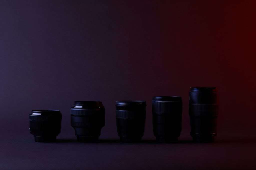 A row of black camera lenses against a dark background, showcasing Camera Basics.