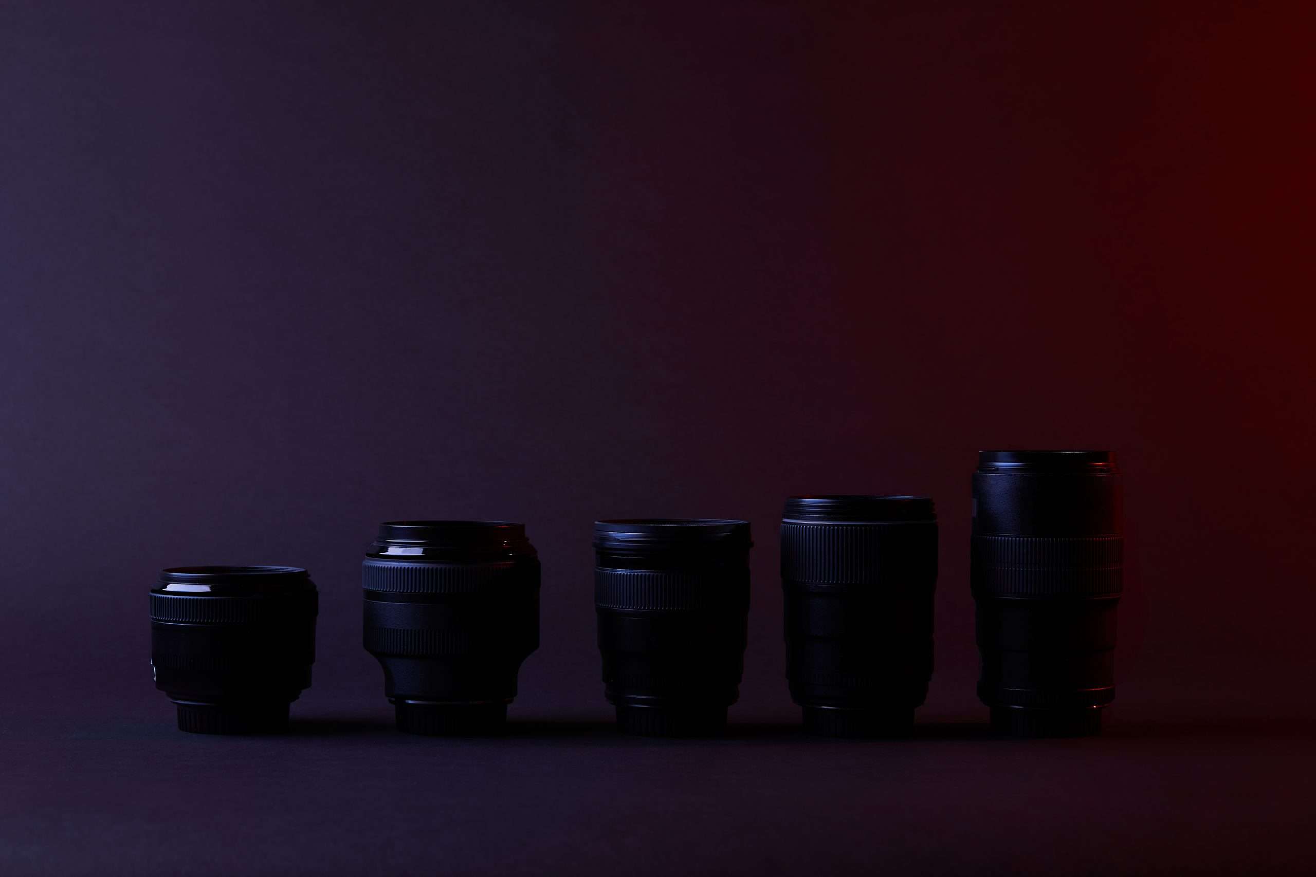 A row of black camera lenses against a dark background, showcasing Camera Basics.