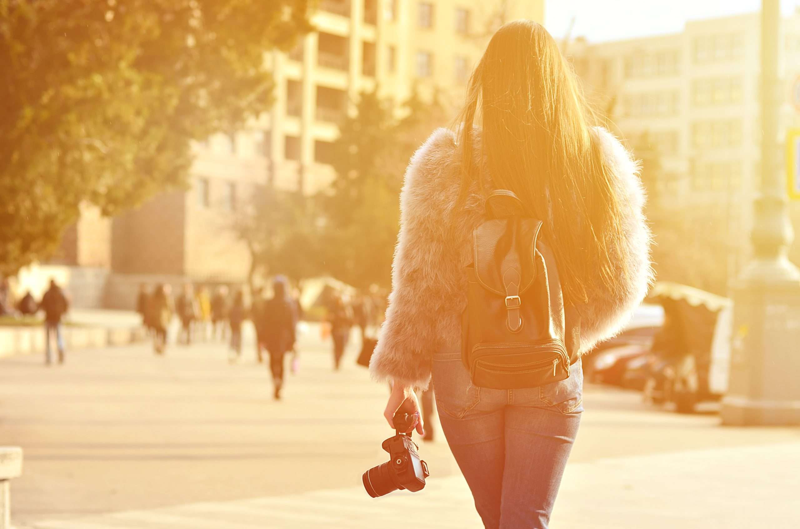 A woman walking down the street with her camera.