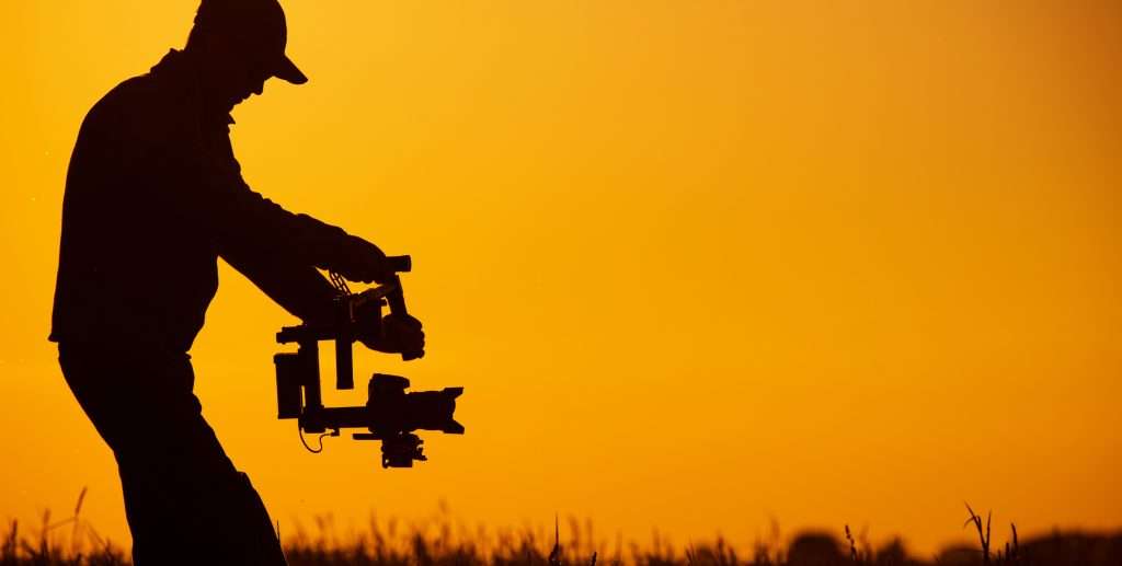 A silhouette of a man holding a camera at sunset.